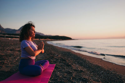 Side view of woman sitting on beach