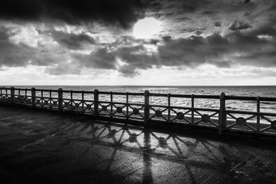 Pier on sea against cloudy sky