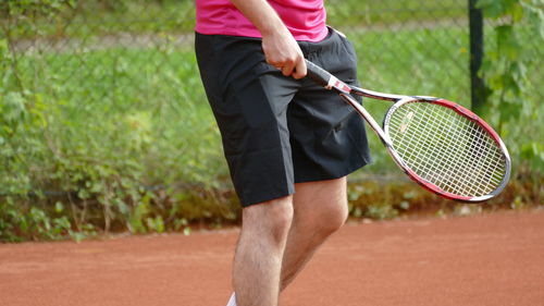 Midsection of man playing badminton in court