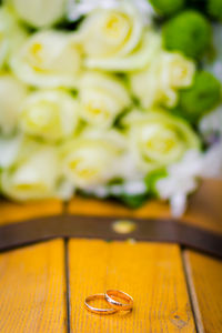 High angle view of wedding rings against defocused roses on table