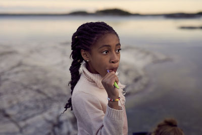 Girl brushing teeth at beach during sunset
