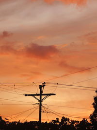 Low angle view of silhouette electricity pylon against romantic sky