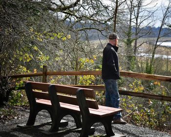 Rear view of man sitting on railing in park