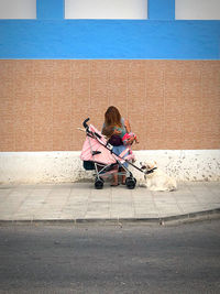 Full length of woman sitting on seat in city