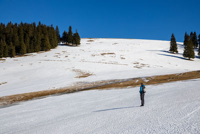 Woman walking on snow covered land against sky