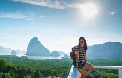 Woman in sunglasses sitting against sky