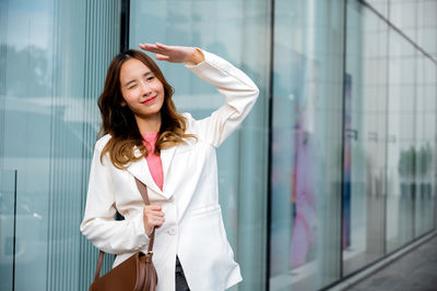 Portrait of young woman standing against wall