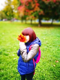 Close-up of girl holding leaves on field