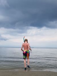 Boy standing on beach against sky