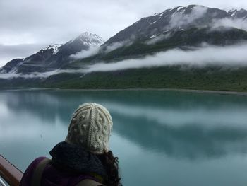 Rear view of woman by lake against snowcapped mountain