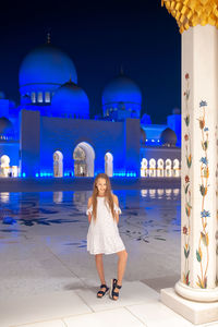 Full length of woman standing against illuminated blue wall