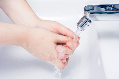 Cropped image of person hand with faucet in water