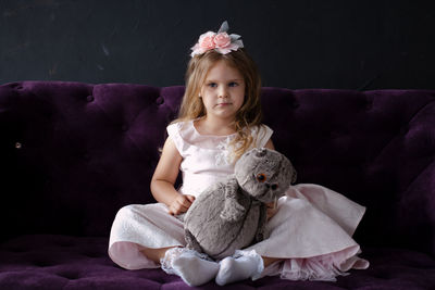 Portrait of cute girl sitting against black background