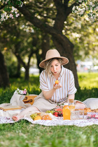 Portrait of woman wearing hat while sitting on field