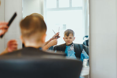 Young boy in mirror getting a haircut in the salon