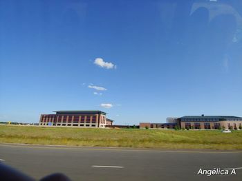 Road by building against blue sky