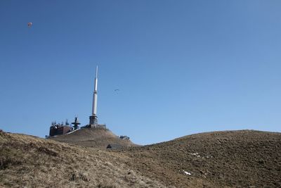 Windmills on landscape against clear blue sky