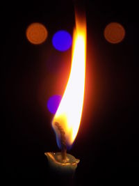 Close-up of lit candle against black background