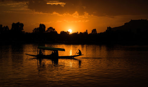 Silhouette boat in lake against sky during sunset