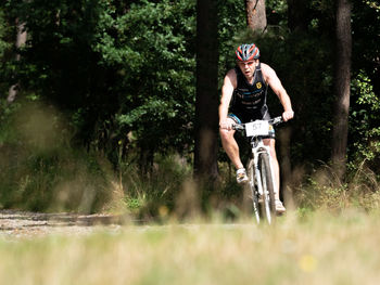 Full length of man riding bicycle in forest