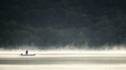 Man standing in boat on lake