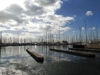 Boats moored at harbor against sky
