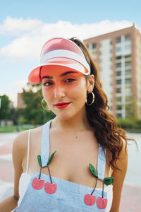 Smiling beautiful woman wearing sun visor standing at sports court