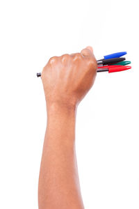 Close-up of hand holding pen against white background