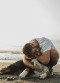 Man gives a hug to his dog on the beach