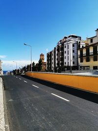Street by buildings against clear blue sky