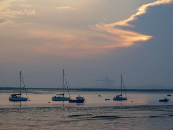 Sailboats in sea against sky during sunset