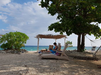 People relaxing on beach against sky