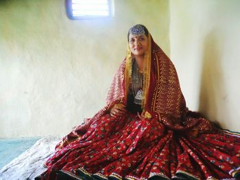 Portrait of woman wearing traditional clothing sitting by wall