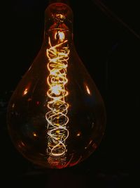 Close-up of illuminated light bulb against black background