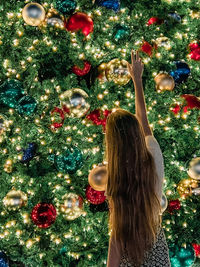 Rear view of woman decorating christmas tree