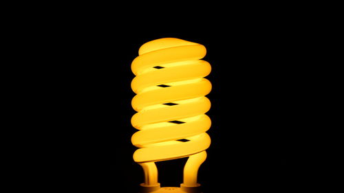 Low angle view of illuminated light bulb against black background