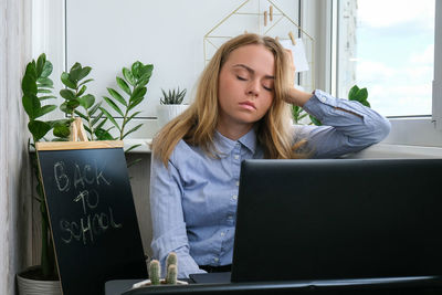 Young woman using phone while sitting on table