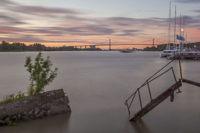 Bridge over river against sky during sunset