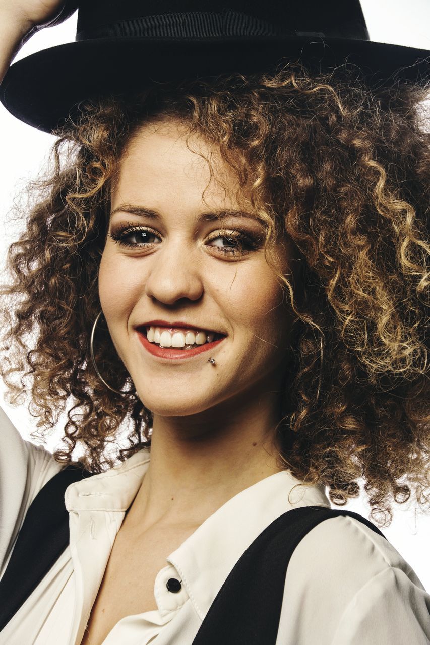 looking at camera, curly hair, portrait, smiling, young adult, young women, one person, real people, headshot, happiness, cheerful, business, day, close-up, outdoors