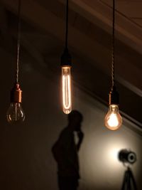 Low angle view of illuminated light bulbs hanging at night