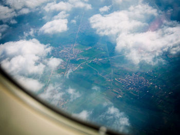 Aerial view of clouds over landscape seen from airplane window