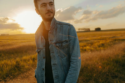 Man standing on field against sky during sunset