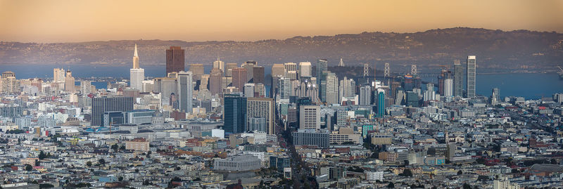 Aerial view of modern buildings in city against sky during sunset