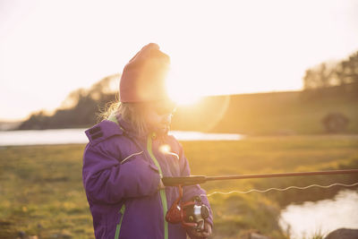 Charming baby fishing in the river at sunset