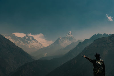 Rear view of man standing on mountain against sky