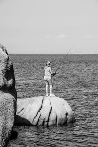 Man fishing in sea against sky