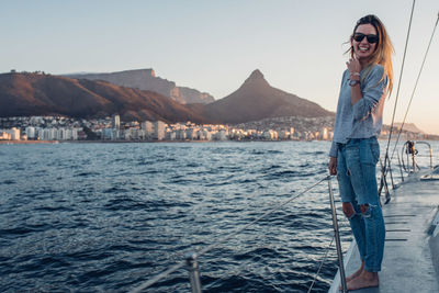 Portrait of young woman standing by sea against clear sky