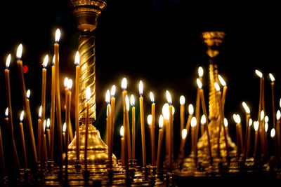 Illuminated candles in temple against black background