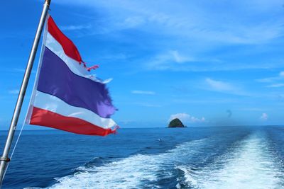 Scenic view of flag on sea against sky