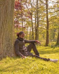 Rear view of man sitting on tree trunk